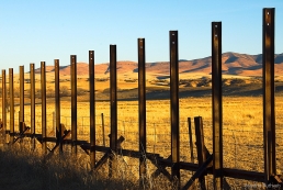 A useless fence marks the border between Mexico (right) and the US at Lochiel, Arizona